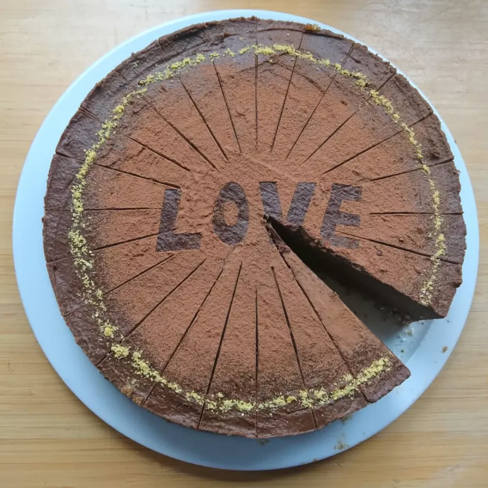A raw chocolate cake with 'LOVE' dusted in cocoa on top